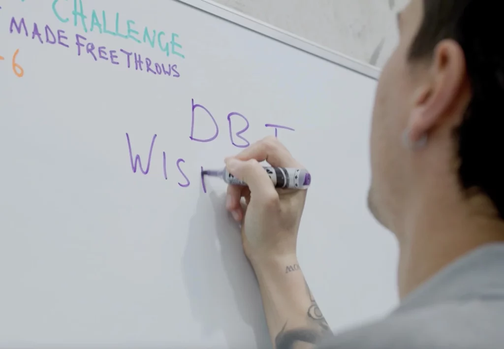 Geelong teen counsellor writing "Challenge: Made Free Throws" on whiteboard, highlighting goal-setting in therapy