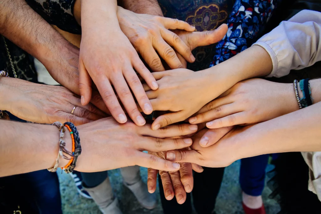 Multiple hands stacked together showing unity and support in youth counselling