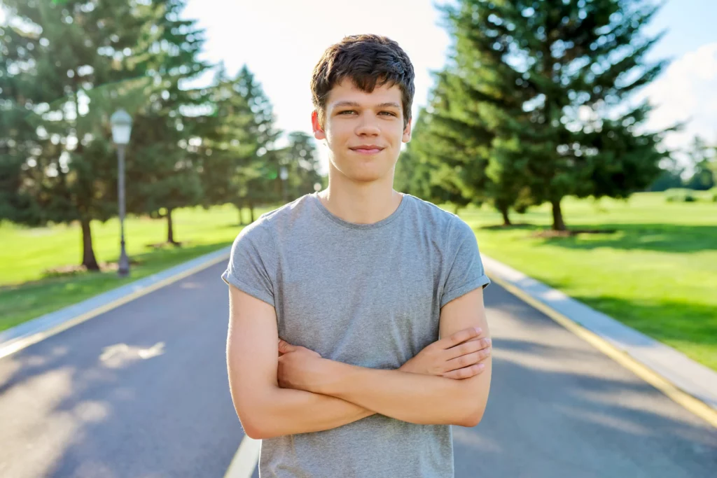 Teenage boy standing confidently on a path surrounded by trees