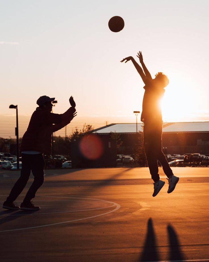 Silhouetted figures playing basketball at sunset, showing a therapeutic counselling session through sports activity